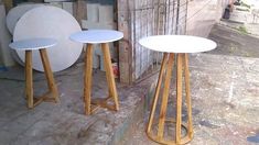 two white tables sitting next to each other on top of a cement floor in front of a building