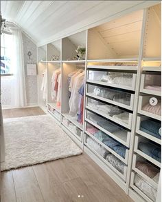 a walk in closet with white shelving and shelves full of clothes on hangers