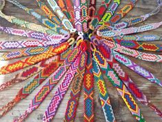 the colorful bracelets are arranged in a circle on top of a wooden table,