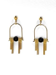 These Art Deco inspired earrings feature sleek, modern design elements, highlighting the contrast between the rich, dark hues of the black, semi precious Agate stone and the radiant golden brass. Each earring boasts a distinctive arched geometric shape inspired by the Art Deco style, lending a sense of elegance and sophistication.  The stepped cut brass fringe creates movement and shine and adds to the uniqueness and contemporary design.  Their minimalist yet bold design embodies a harmonious balance between simplicity and intricacy, making them a versatile accessory suitable for both formal occasions and everyday wear. Each earring is finished with a brass ball stud with stainless steel post. Approximate measurements- 4.5 long 1.5cms wide All Set Theory Jewellery comes with care instructi Modern Gold Earrings With Black Enamel, Modern Gold Onyx Jewelry, Gold Onyx Earrings For Evening, Modern Metal Linear Earrings For Evening, Modern Brass Earrings For Evening, Modern Black Enamel Drop Earrings, Modern Black Enamel Earrings For Gift, Modern Yellow Gold Linear Earrings, Modern Black Enamel Earrings As Gift