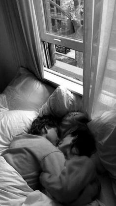 black and white photograph of a person sleeping on a bed in front of a window