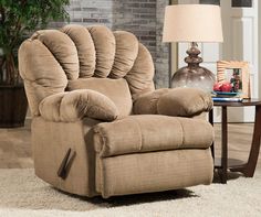 a living room with a brown recliner and a lamp on the side table in front of a brick wall