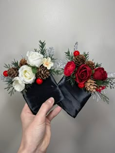 two black boxes with red and white flowers on them are being held up by someone's hand