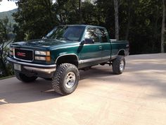 a green pick up truck parked on top of a driveway