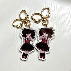 two keychains with anime characters on them sitting next to each other in front of a white surface