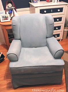 a blue recliner chair sitting on top of a hard wood floor next to a dresser