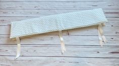 a baby crib bumper made out of white chevron fabric on wood planks