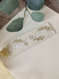 there is a white table cloth with the word congratulations on it and some green leaves