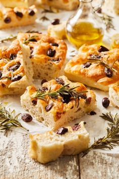 bread with olives, rosemary and oil on a white tablecloth next to other food items