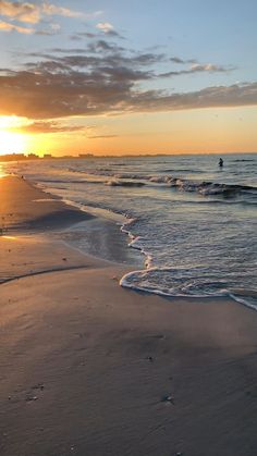 the sun is setting over the water at the beach