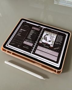 a tablet computer sitting on top of a table next to a white pen and paper