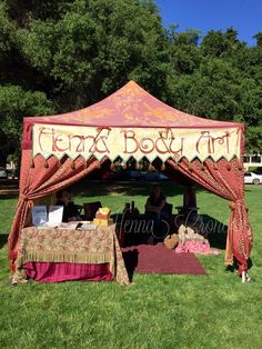 a tent that is in the grass with people sitting at it and writing on it