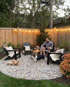 a man sitting in a backyard with his dog and fire pit surrounded by graveled area