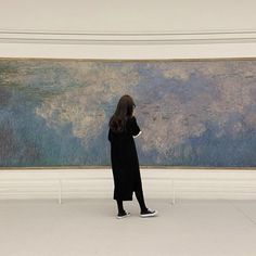 a woman standing in front of a large painting