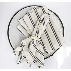 a white plate topped with a black and white striped napkin tied to it's side