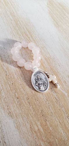 This mini rosary is beautiful, perfect size to keep in your hand, pocket, purse.  This one decade finger rosary is made using 10 8mm smooth round rose quartz beads. The beads are strung into nylon thread and accented with a small cream howlite cross. This rosary features a St. Lucy medallion, made in Italy Finger Rosary, Small Rosary, St Lucy, Saint Lucy, Mini Rosaries, Saints Medals, Santa Lucia, Rose Quartz Beads, Pray For Us