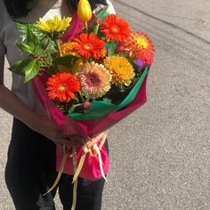 a woman holding a bouquet of colorful flowers