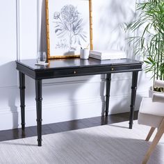 a black table with two books and a vase on it in front of a white wall