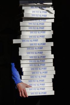 a stack of books that have been stacked on top of each other with one person's hand pointing at them