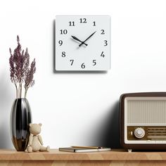 there is a clock on the wall next to a radio and a vase with flowers