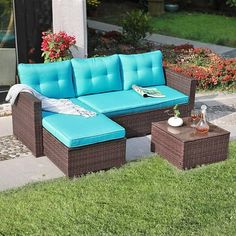 a blue couch and ottoman sitting on the side of a sidewalk next to flowers in vases