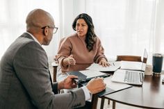 a man and woman sitting at a table talking to each other