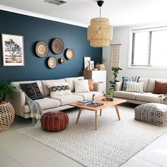 a living room filled with lots of furniture next to a wall covered in plates and plants