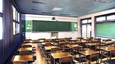 an empty classroom filled with wooden desks and green chalkboard mounted to the wall