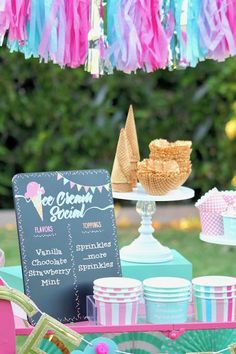 an ice cream stand is set up with pink, blue and green paper streamers