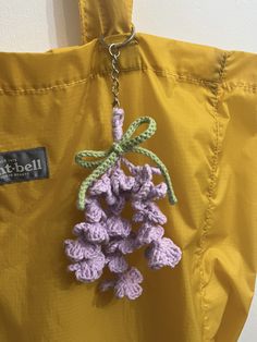 a crocheted keychain hanging from a yellow jacket with purple flowers on it