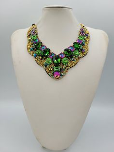 Each piece of our statement necklaces is handmade and one of a kind made in Italy. Our creations is made of high quality materials such as crystals and rhinestones. Each embroidered material is carefully hand sewn. Very glamorous and stylish. Perfect gift to someone you like. Materials Strass stone and Rhinestone in Violet, Rainbow, Emerald, Peridot and Violet Blue color in different dimension.  Black satin fabric backing. Aluminium chain with lobster closure. Measurements Weight approximate 200 grams. Chain lenght 25 cm - 9.84 in Circumference approximate 63 cm - 24.80 in Feel free to contact us if you have any question. Thank you so much for looking at our shop and our articles each of them, single piece. Green Crystal Necklace With Stones, Green Crystal Necklace With Jewels, Green Beaded Choker Necklace For Party, Green Beaded Choker For Party, Green Costume Jewelry Necklace, Green Jeweled Necklace For Party, Handmade Party Pendant Crystal Necklace, Handmade Green Crystal Necklaces, Party Choker Necklace With Stones