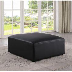 a large black ottoman sitting on top of a rug in front of a sliding glass door