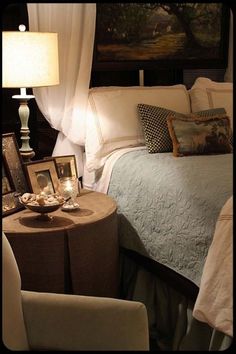 a bed sitting under a painting next to two chairs and a table with a lamp on it