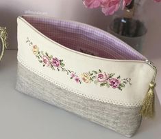 a white purse sitting on top of a table next to a vase with pink flowers