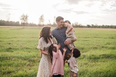 a man and two children are standing in the grass with their arms around each other