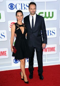 a man and woman are standing on the red carpet at an awards event in black dresses