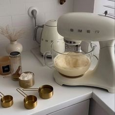 a kitchen counter with gold measuring cups and an electric mixer on it's side