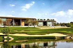 a large house sitting on top of a lush green field next to a body of water