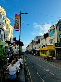 people are sitting on benches in the middle of an empty street with shops and buildings