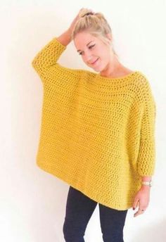 a woman wearing a yellow crochet sweater and leggings stands in front of a white wall