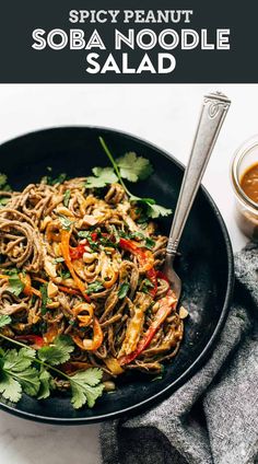 a black plate topped with noodles and vegetables, garnished with cilantro