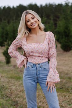 This is our gorgeous "In Full Bloom Top". From the smocked trumpet sleeves to the beautiful floral print, this blouse is ALL about the details. We suggest pairing it with our "Go Your Own Suede Shorts" or our "Zip it Skirt". The fit is true-to-size. The back can be tied and adjusted to your liking. Our model is 5'4", 112 pounds, and is wearing a size small. Trendy Fitted Smocked Top With Gathered Sleeves, Fitted Tops With Gathered Sleeves For Brunch, Fitted Smocked Top With Gathered Sleeves For Brunch, Long Sleeve Smocked Top For Spring Day Out, Spring Long Sleeve Tops With Smocked Cuffs, Long Sleeve Smocked Top With Smocked Cuffs For Spring, Spring Long Sleeve Blouse With Smocked Bodice, Long Sleeve Peasant Top With Smocked Bodice For Spring, Long Sleeve Blouse With Smocked Bodice For Spring