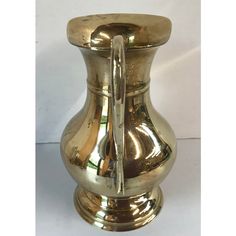 a gold colored vase sitting on top of a white table