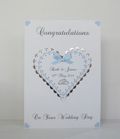 a wedding card with a heart on the front and blue ribbon in the middle, which reads congratulationss