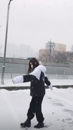 a person is walking in the snow with an umbrella over their head and one arm stretched out