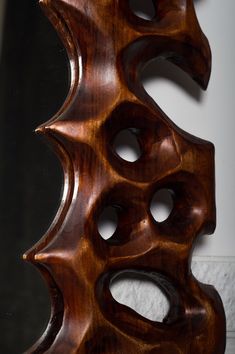 a wooden sculpture sitting on top of a table next to a mirror with holes in it