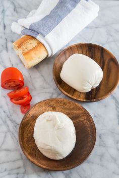 two plates with bread and tomatoes on the table next to each other, one has a piece of bread in it