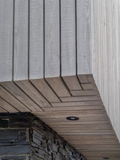 a black and white cat sitting on top of a wooden bench next to a building