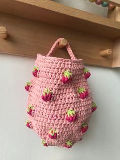 a pink crocheted purse hanging from a hook