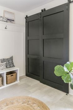 a living room with black sliding doors and white shelves on the wall next to a plant